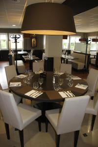 uma sala de jantar com uma mesa preta e cadeiras brancas em Le Bistroquet em Lusignan