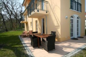 a patio with a wooden table and chairs in front of a house at Haus Meeresblick B 001 Sebastus mit Terrasse in Baabe