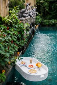 un tavolo con cibo e bevande accanto alla piscina di Desak Putu Putra Hidden ad Ubud