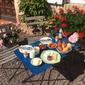 Le Vert Buisson في Cartigny-lʼÉpinay: طاولة زرقاء مع الطعام والبيض والخبز