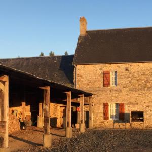 an old stone house with a black roof and a building at Le Vert Buisson in Cartigny-lʼÉpinay