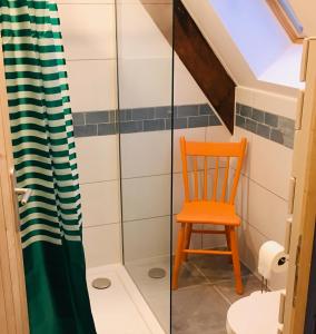 a bathroom with a shower and a orange chair at Le Vert Buisson in Cartigny-lʼÉpinay