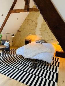 a bedroom with a bed on a black and white rug at Le Vert Buisson in Cartigny-lʼÉpinay