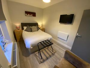 Habitación pequeña con cama y TV de pantalla plana. en The Fordham Inn en Sharnbrook