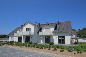 a large white house with a roof at Haus Düne Whg 03 mit SüdWest Terrasse und Balkon in Thiessow