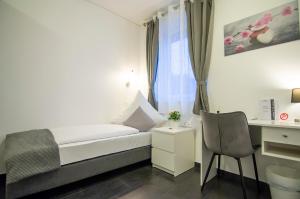 a bedroom with a bed and a desk and a chair at Hotel L201 - 24h self-check in in Gablitz