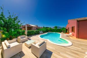 einen Hinterhof mit Pool und Stühlen und ein Haus in der Unterkunft Luxury Villas in Lascari