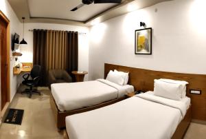 a hotel room with two beds and a desk at Green Hills Cottage Rishikesh in Rishīkesh