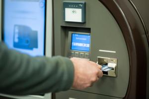 una persona está poniendo un billete en una máquina de cajero automático en Hotel L201 - 24h self-check in, en Gablitz