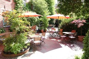 un patio al aire libre con mesas, sillas y sombrillas en Altstadthotel Twardokus, en Aurich