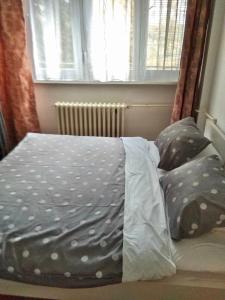 a bed with polka dot sheets and a window at Apartman Olivia in Banja Luka