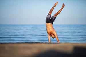 una persona che fa una verticale di fronte all'oceano di Three Corners Equinox Beach Resort a Abu Dabab