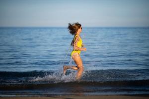 Three Corners Equinox Beach Resort في أبو دباب: امرأة تهرب في الماء على الشاطئ