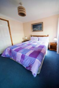 a bedroom with a large bed with a purple comforter at Oliver's Seafood Bar, Bed & Breakfast in Cleggan