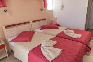 two beds in a bedroom with red and white blankets at Maistrali in Karavostasi