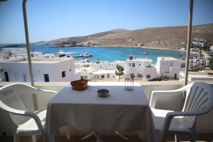 a table with white chairs and a view of a harbor at Maistrali in Karavostasi