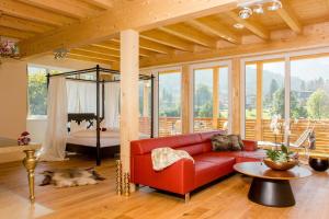 a living room with a red couch and a bed at Hotel Garni Berghof in Pertisau