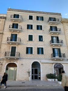 un grande edificio in mattoni con finestre e persone che camminano davanti di Le Dimore di Don Corrado a Trani