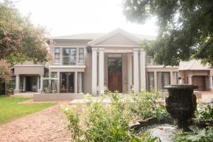 une grande maison avec une fontaine en face de celle-ci dans l'établissement Potch Manor Boutique Guest House, à Potchefstroom