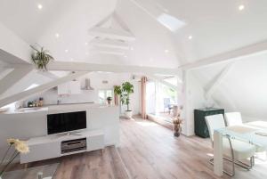 a white living room with a table and a tv at Haus Behr am See in Radolfzell am Bodensee