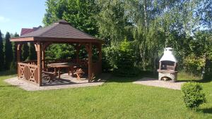 a wooden gazebo with a grill in a yard at Willa Promyk in Gdańsk