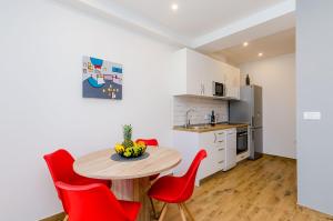 a small kitchen with a table and red chairs at Apartment Moon River in Mokošica