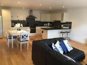 ein Wohnzimmer mit einem schwarzen Sofa und einer Küche in der Unterkunft Strandview Ground Floor Beach Apartment in Ballycastle