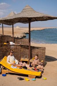 a group of people sitting on the beach at Three Corners Sea Beach Resort in Coraya Bay