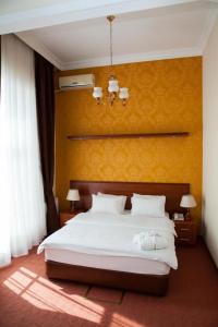 a bedroom with a white bed with a yellow wall at Azcot Hotel in Baku