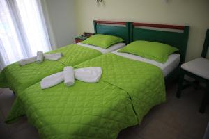 two beds with green comforters and bows on them at Maistrali in Karavostasi