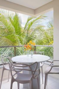 uma mesa branca com cadeiras e um vaso com flores em Flat Super Luxo Carneiros Beach Resort em Tamandaré