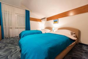 two beds in a hotel room with blue sheets at Villa Jablanica Lake in Jablanica