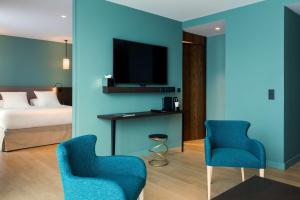 a hotel room with blue walls and two chairs and a bed at Hotel L'Arbre Voyageur - BW Premier Collection - LILLE in Lille