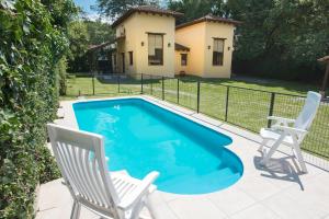 una piscina con 2 sillas y una casa en Cabañas La Escondida en San Lorenzo