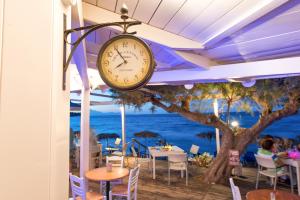 a clock hanging from the ceiling of a restaurant at Fiore Beach Studios in Vasilikos