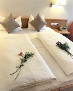 two white beds with flowers on top of them at Hotel Austria Stuttgart-City in Stuttgart