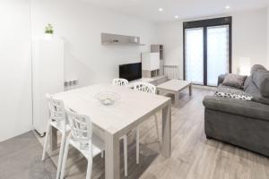 Il dispose d'une cuisine et d'un salon avec une table et des chaises blanches. dans l'établissement Apartamentos La Catedral 2º B - Pleno Centro, à Logroño