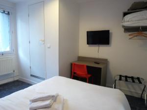 een kamer met een bed, een bureau en een televisie bij Hotel le Faisan in Saint-Avertin