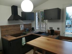 uma cozinha com um lavatório e uma mesa de madeira em Chambre avec tout le confort d'un appartement em Villeneuve-lès-Avignon