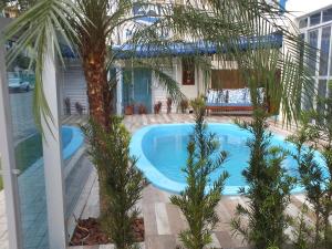 a swimming pool with a palm tree in front of a house at Residencial Praia Mar in Florianópolis