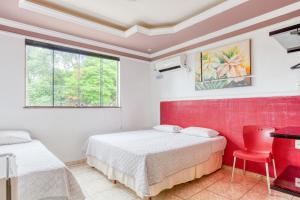 a bedroom with two beds and a desk and a window at Ouro Hotel in Vespasiano