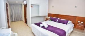 a bedroom with a large bed with purple pillows at Sunec Hotel in Chiclayo