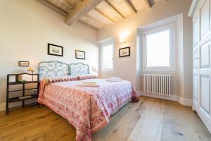 een slaapkamer met een bed met een roze sprei en 2 ramen bij Oltrarno Real Mood Florentine Apartment in Florence