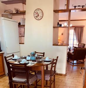 a dining room table with chairs and a clock on the wall at Vravrona Family House in Artemida