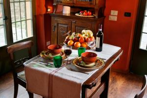 una mesa con un bol de fruta y una botella de vino en I Veroni - Agriturismo and Wine Cellar, en Pontassieve
