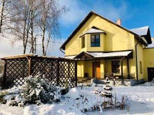 a yellow house with snow on the ground at Rudzupuķes in Svente