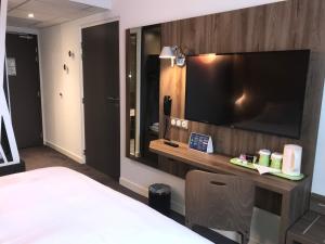 una habitación de hotel con una gran TV en la pared en Campanile Findrol Annemasse Savoie Leman, en Fillinges