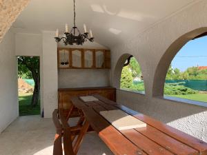 ein Esszimmer mit einem Holztisch und 2 Fenstern in der Unterkunft Pellegrini Apartman in Balatonakali