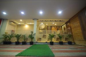 a lobby with plants and a green rug at Hotel White Mount in Chennai