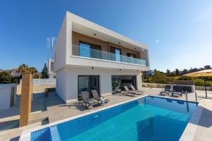 a villa with a swimming pool and a house at Villa Marlene, walking distance to Coral Beach! in Peyia